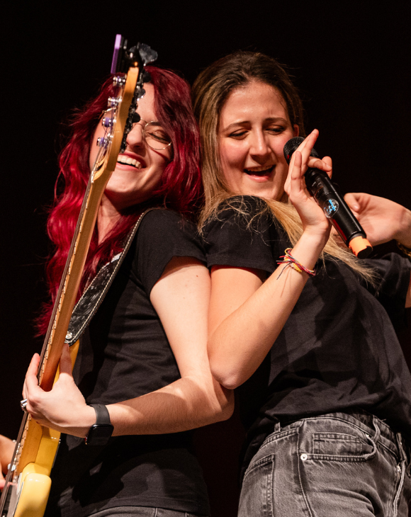 Studente della Scuola e Accademia di Musica Cluster suona il basso elettrico durante una performance live, con amplificatore Markbass e batteria sullo sfondo